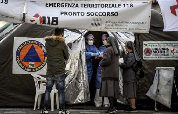 Monjas conversan con paramédicos en una carpa instalada por Protección Civil junto a la sala de emergencias del hospital Piacenza, en el norte de Italia, que ya reporta 17 decesos por el Covid-19.Foto Ap.