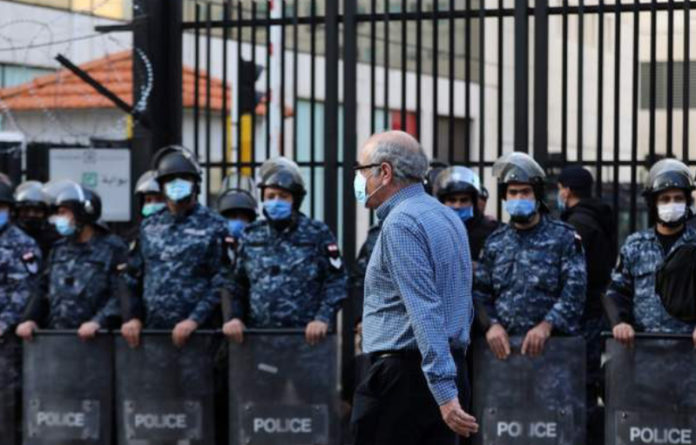 En la imagen, un hombre libanés camina junto a miembros de las fuerzas de seguridad en Beirut. Foto Afp.