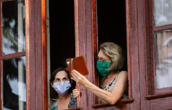 Dos mujeres conversan desde su vivienda en La Habana. Foto Ap.