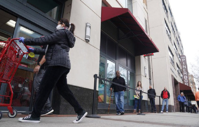 Personas toman distancia mientras esperan para ingresar a un supermercado en Arlington, Virginia. Foto Xinhua.