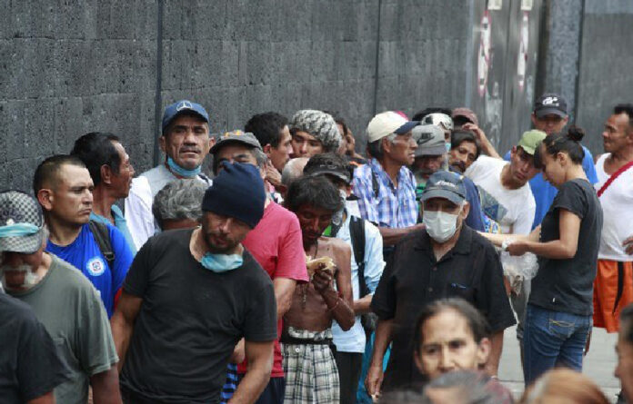 Personas en situación de calle esperan recibir una ración de comida a las afueras del Teatro Blanquita. Foto Alfredo Domínguez.