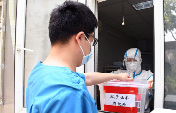 Médico lleva muestras tomadas de pacientes para realizar pruebas de detección de Covid-19 en en el Hospital de Haidian, en Pekin, China. Foto Xinhua.