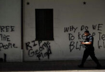 Un miembro del Servicio Secreto de EU pasa junto a un graffiti cerca de la Casa Blanca, tras una noche de protestas por la muerte de George Floyd. Foto Afp.