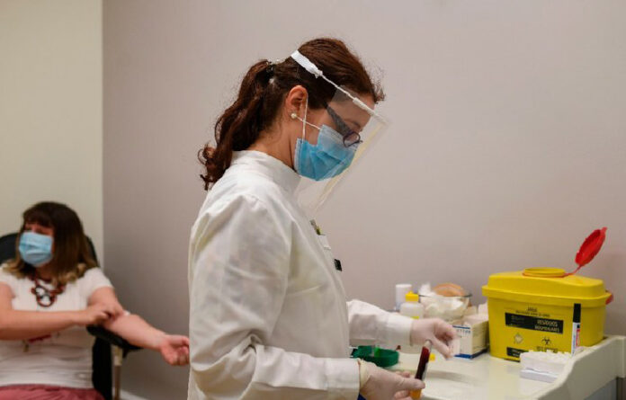 Una enfermera, en Lisboa, recolecta una muestra de sangre para prueba de Covid-19. Foto AFP.