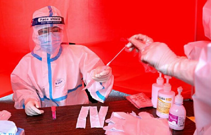 Un trabajador médico recolecta una muestra de una persona para hacer la prueba del coronavirus, en Mudanjiang, China. Foto Afp.