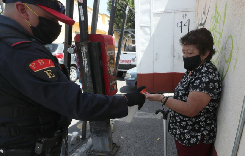 Policía capitalino ofrece gel antibacterial a peatona en la alcaldía Álvaro Obregón. Foto LA JORNADA/José Antonio López.