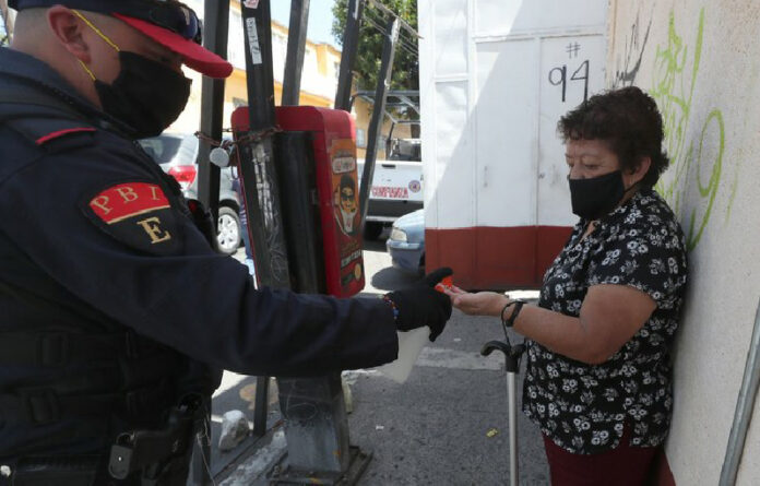 Policía capitalino ofrece gel antibacterial a peatona en la alcaldía Álvaro Obregón. Foto LA JORNADA/José Antonio López.