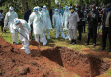 Miembros del equipo de aislamiento del condado de Bungoma entierran el ataúd del doctor Doreen Lugaliki, de 39 años, el primer médico keniano fallecido de Covid-19 en Nairobi, Kenia. Foto Afp.