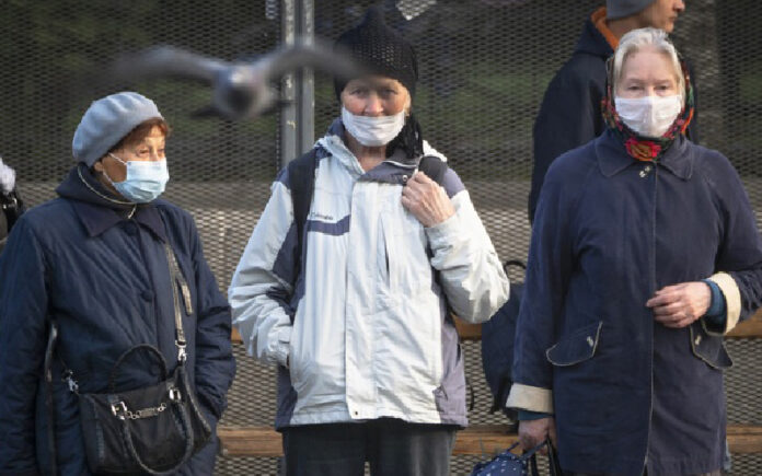 Mujeres con cubrebocas para evitar contagiarse de coronavirus esperan al autobús en San Petersburgo, Rusia. Foto Ap.