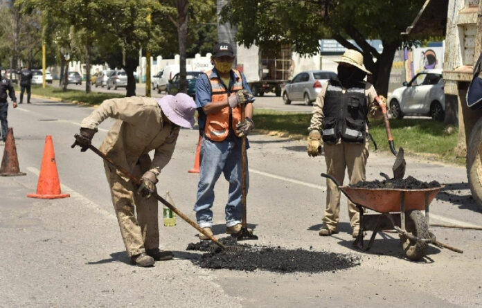 Cuadrillas de trabajadores realizan acciones preliminares con la aplicación de balastre de cantera para absorber la humedad y garantizar la durabilidad del bacheo.