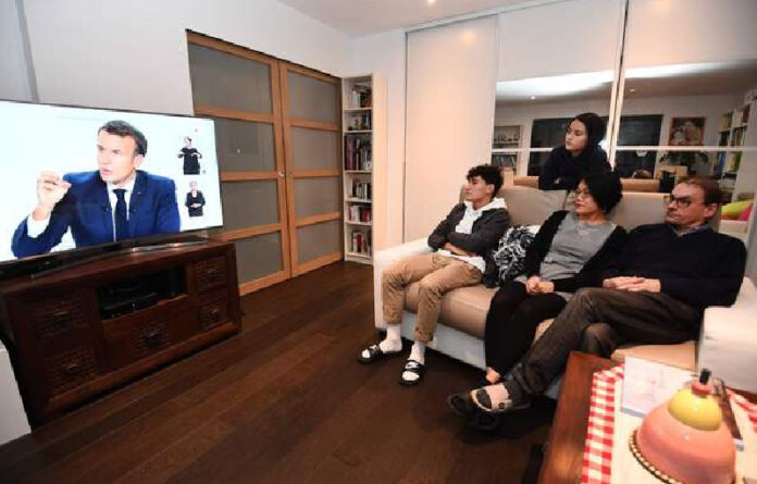 Una familia ve en televisión el anuncio del presidente Emmanuel Macron del nuevo toque de queda para frenar al coronavirus, en Fouesnant, al oeste de Francia. Foto Afp.