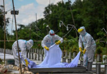 Voluntarios con equipo de protección entierran a una víctima de coronavirus en un cementerio de Rangún, Birmania. Foto Afp.