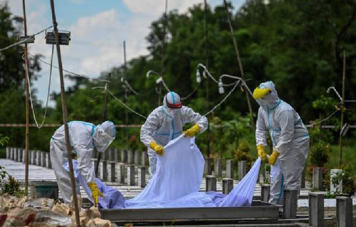 Voluntarios con equipo de protección entierran a una víctima de coronavirus en un cementerio de Rangún, Birmania. Foto Afp.