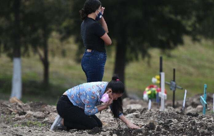 Una mujer solloza ante la tumba de su abuela, víctima del Covid-19, en un cementerio en Tegucigalpa, Honduras. Foto AFP.