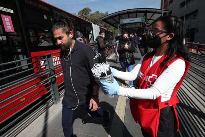 Voluntarios de la Cruz Roja Mexicana entregan cubrebocas a la salida de una estación de Metrobús en la CDMX. Foto José Antonio López / Archivo.